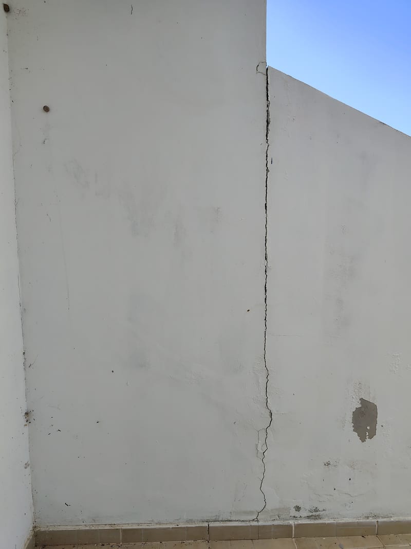 A long vertical crack in a white outside wall